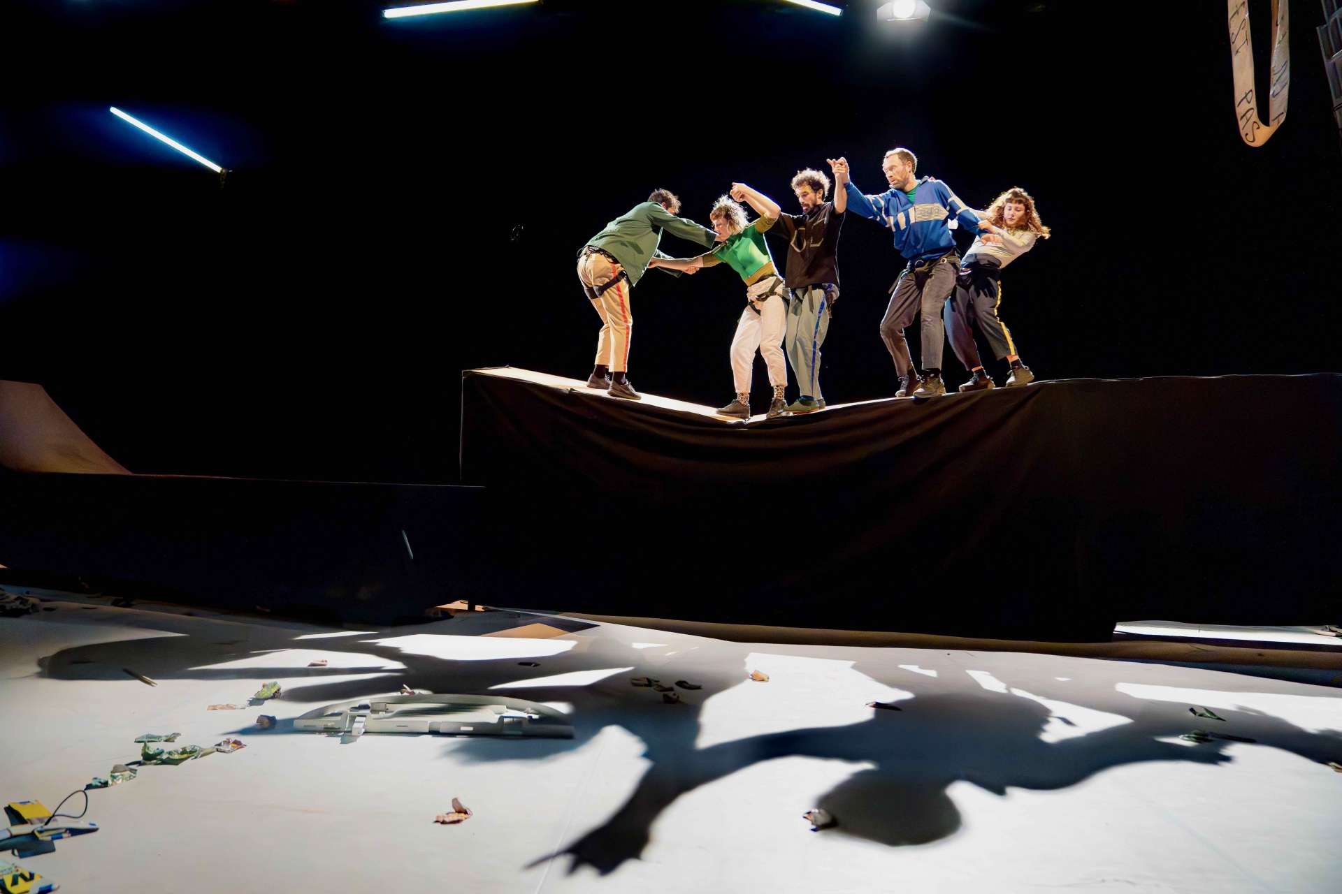 Image du spectacle "Frasques", cinq circassiennes et circassiens en équilibre sur une fine structure souple. Ils et elles semblent interagir, se tenant debout et en se penchant les uns vers les autres. 