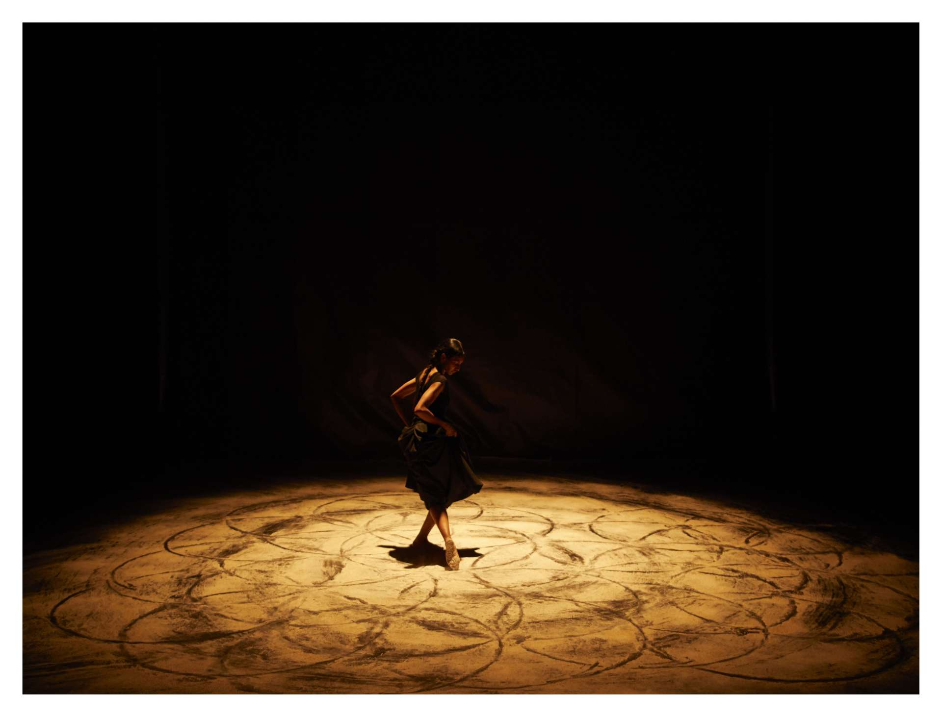 La danseuse Shantala Shivalingappa dessine un mandala cendré au sol avec ses pieds. 