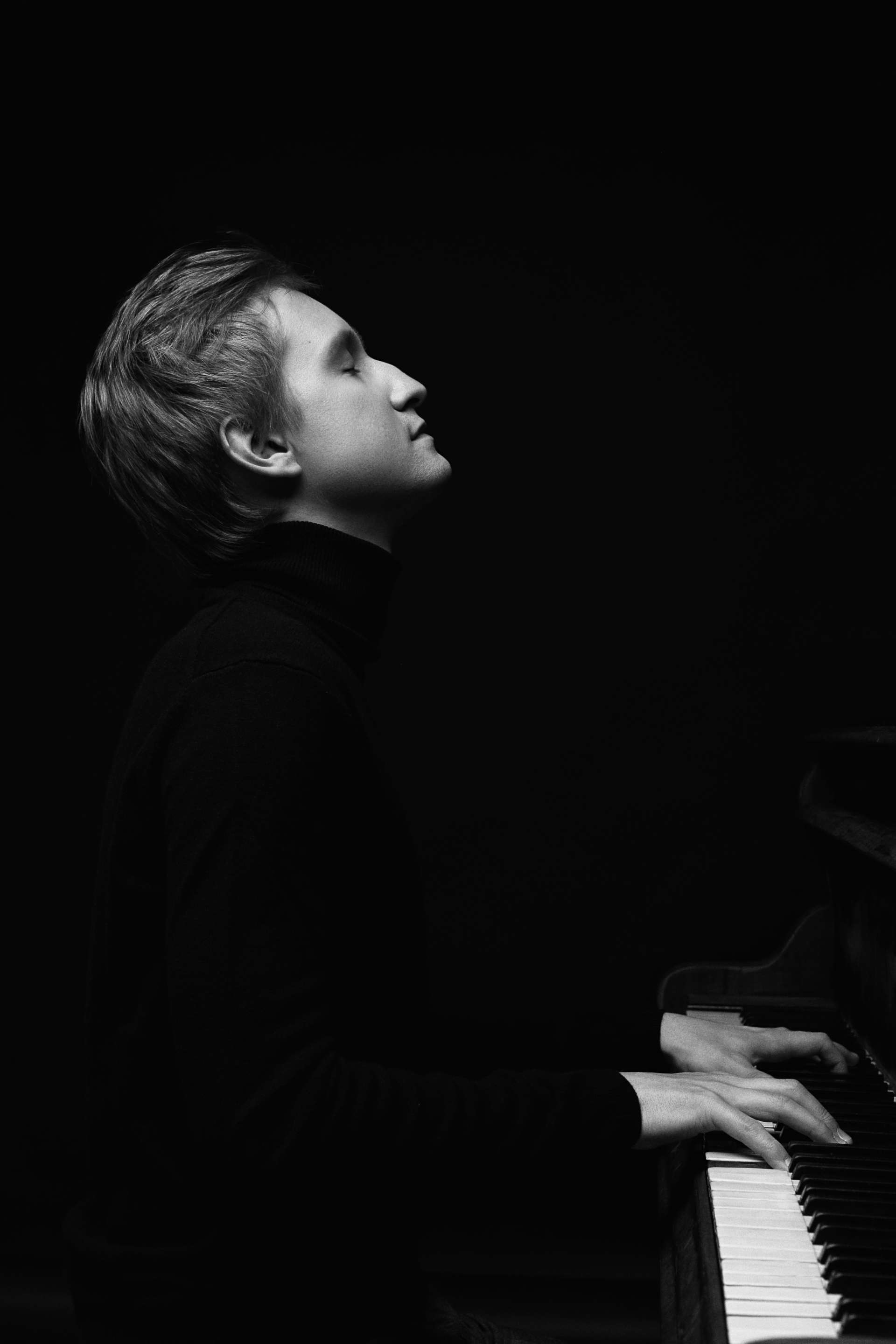 Portrait noir et blanc de Dmitry Masleev jouant du piano. 