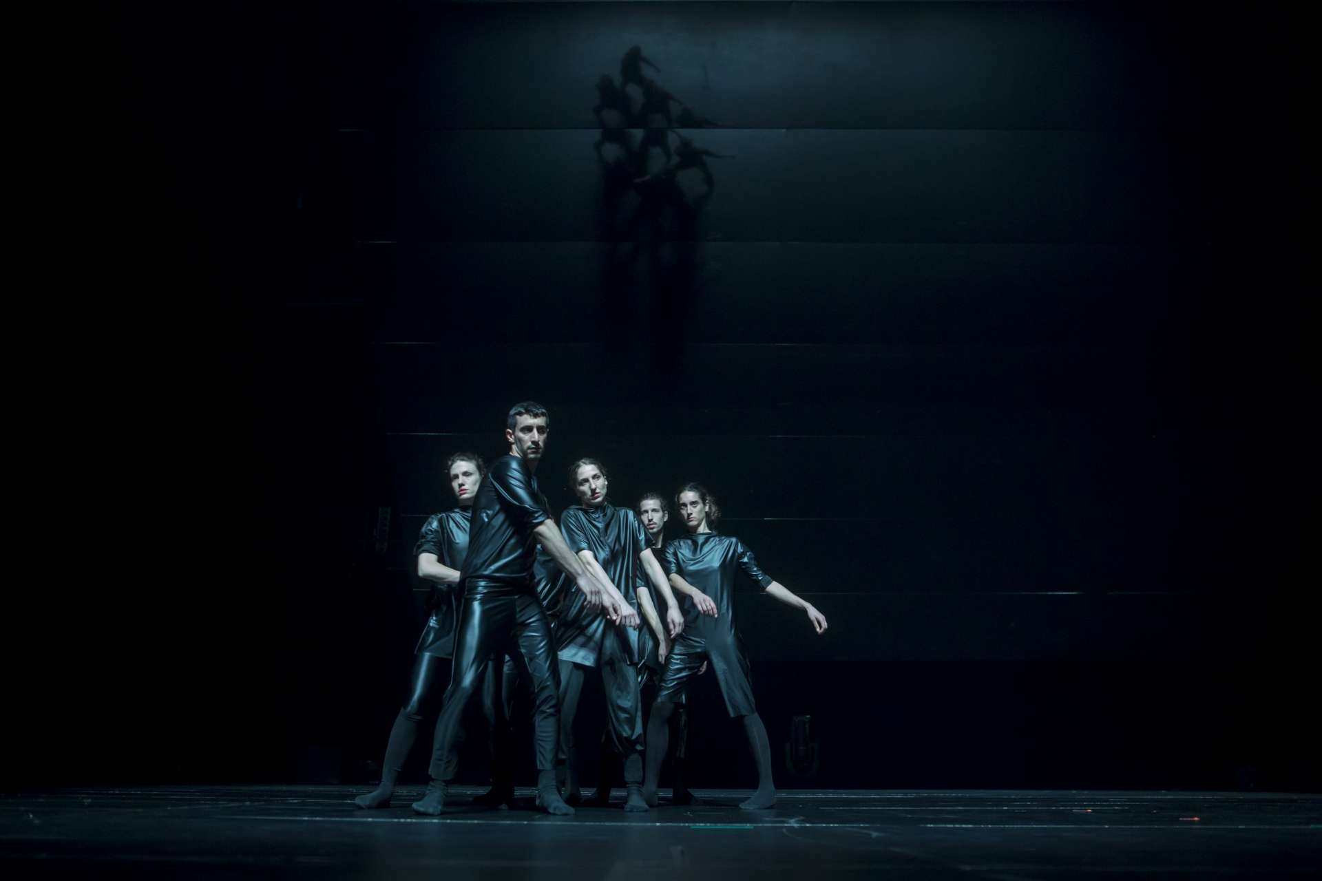 Sur scène fond noir, cinq danseurs/danseuses en costume bleu glacier 