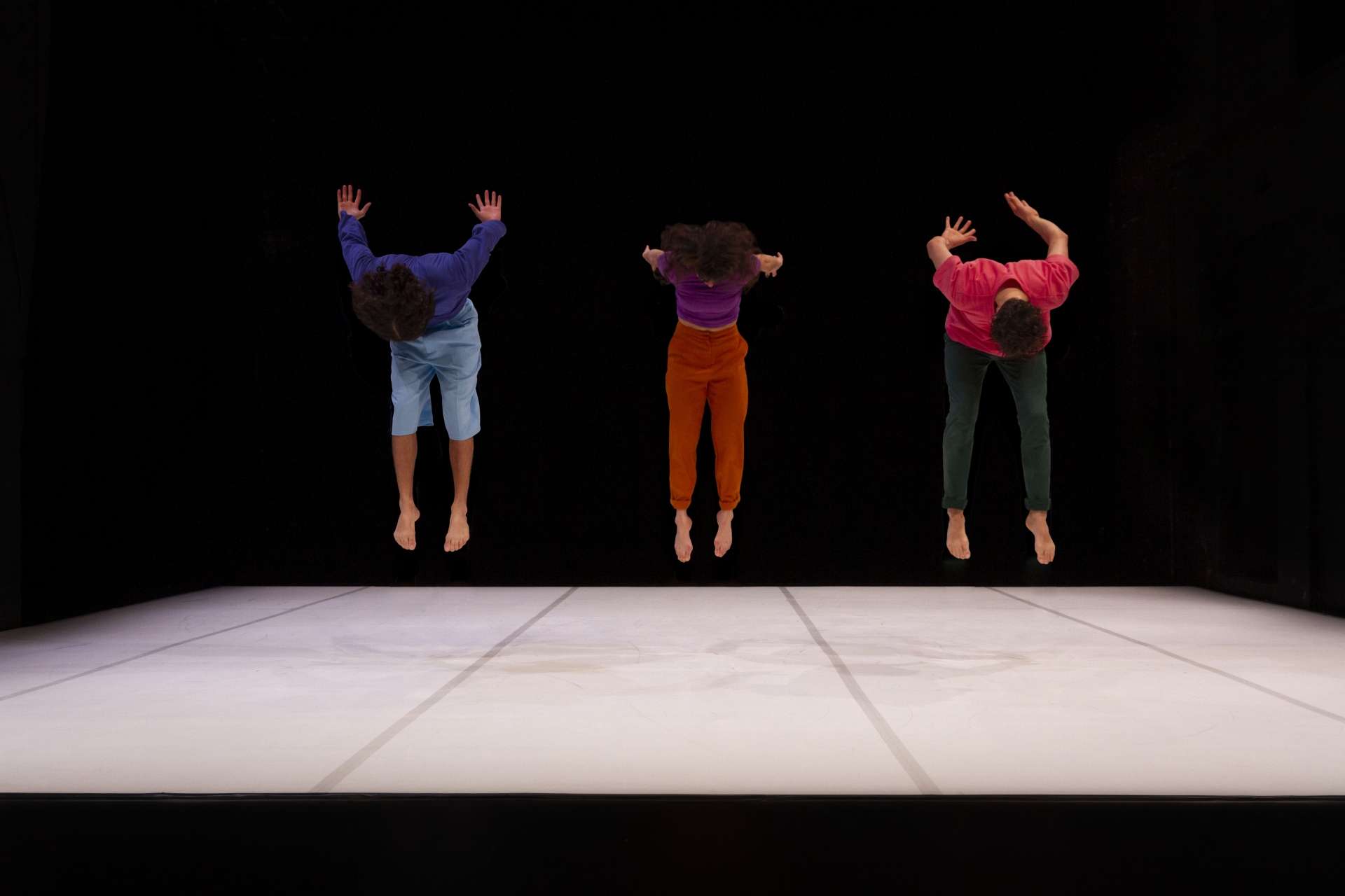 Les trois artistes circassiens sont en plein saut, comme suspendu en l'air. 