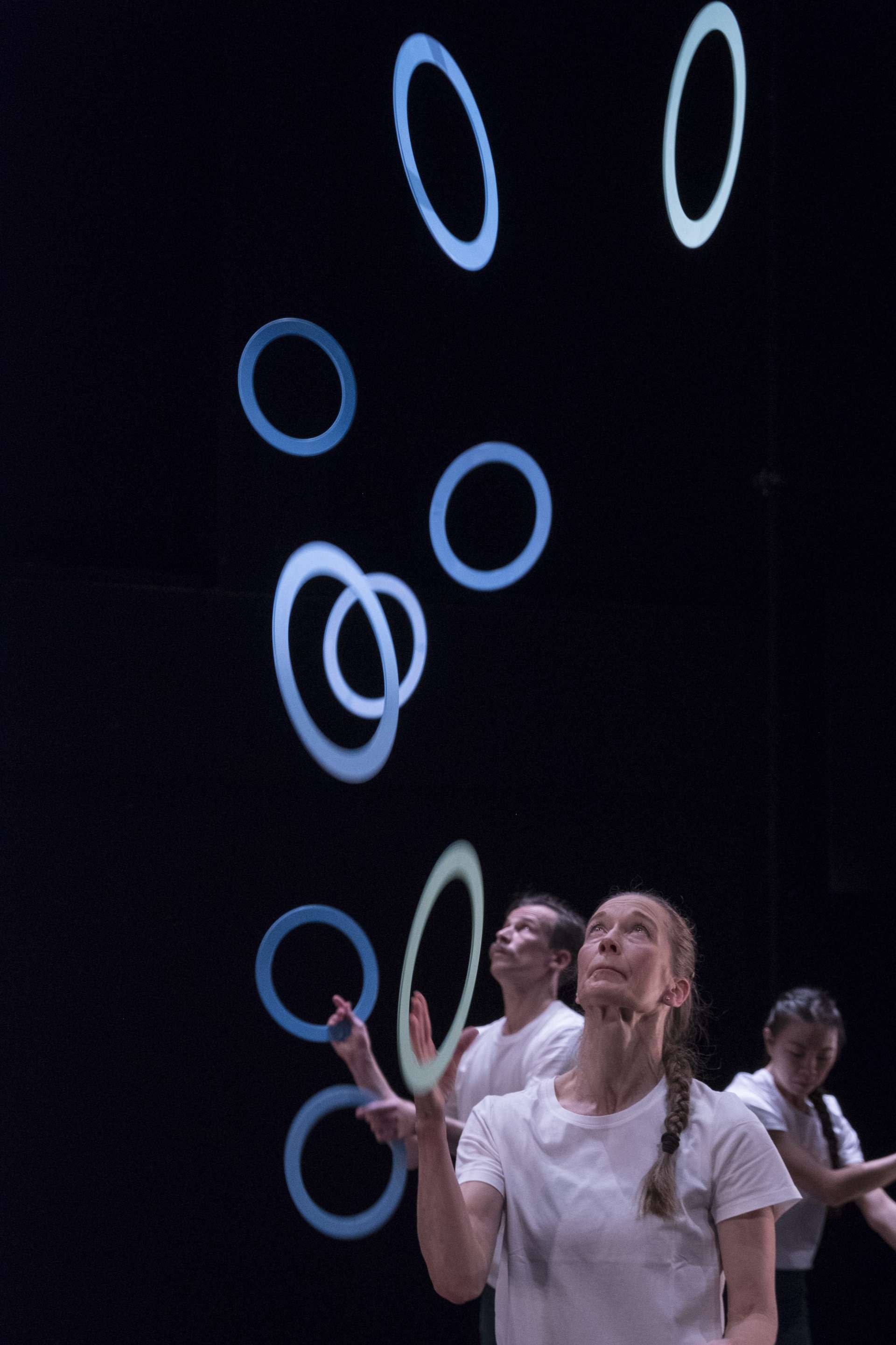 Au premier plan, la jongleuse Erin O’Toole qui jongle avec des cerceaux bleus. 