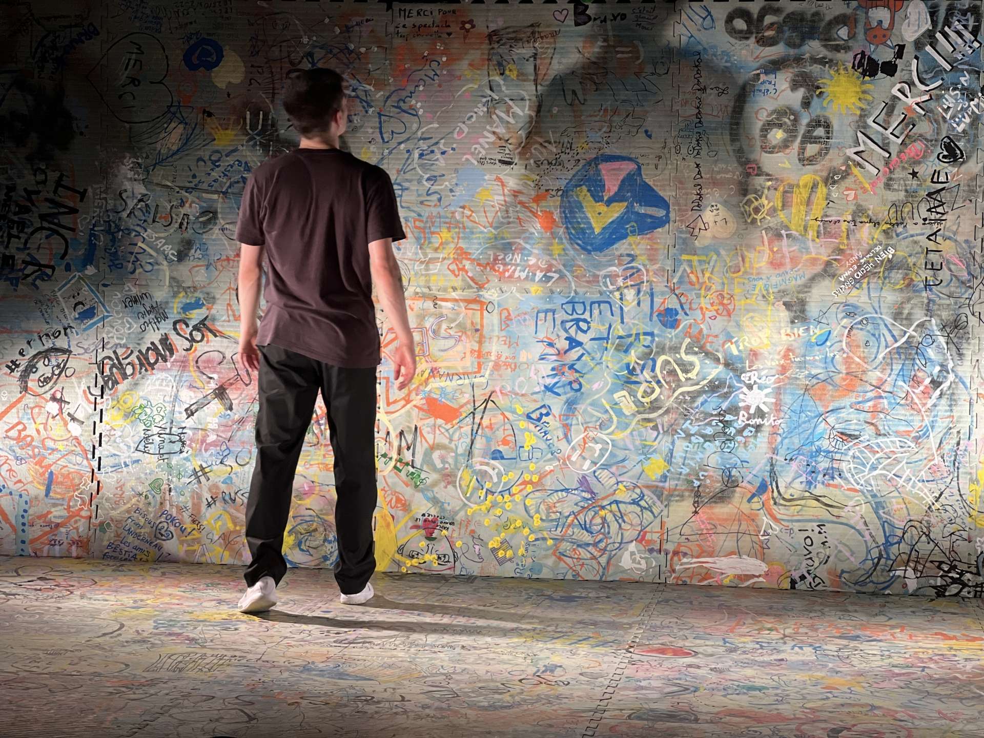 Paul Molina de dos et face à un mur de street art. 