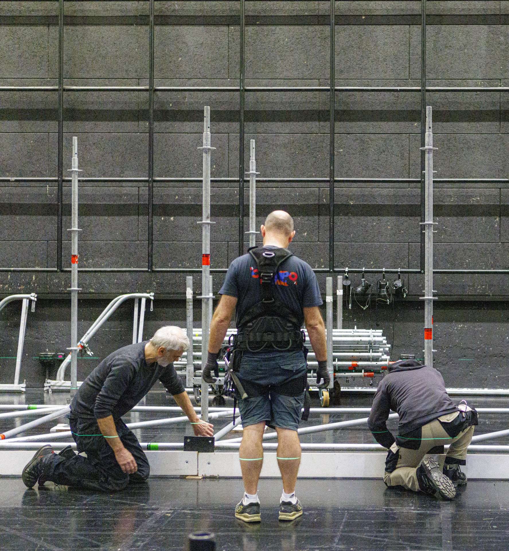 Trois techniciens règlent le niveau des planches installés au sol.
