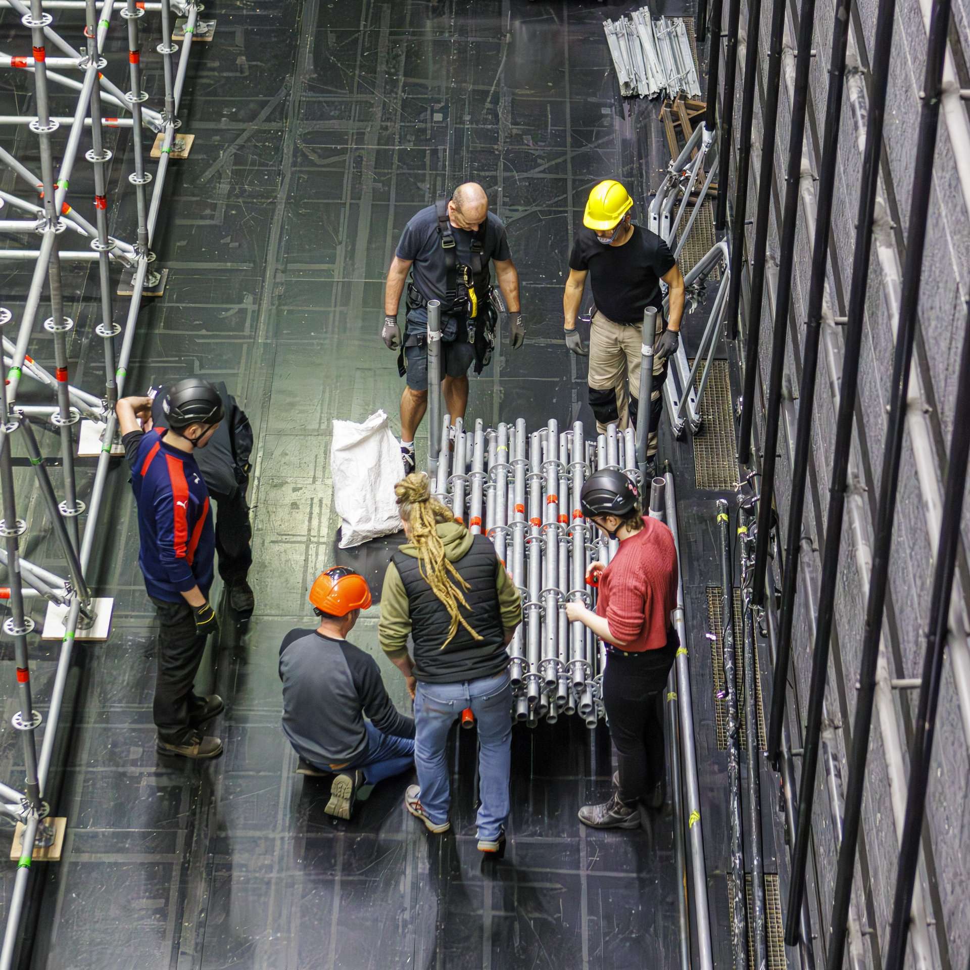 Plusieurs techniciens prennent des barres en métal posées en tas sur le plateau.