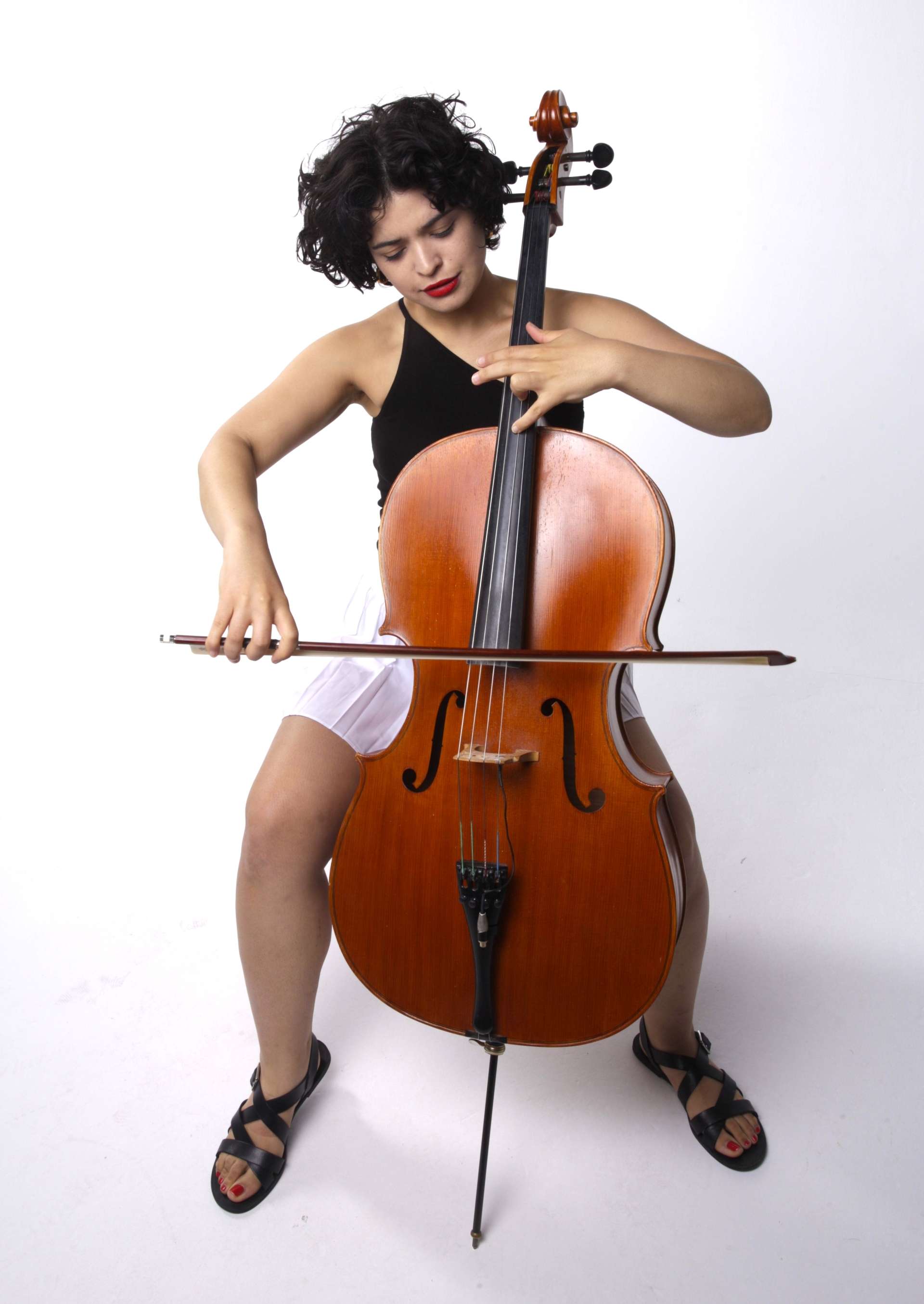 Photo studio. Plan en pied de face d'Ana Carla Maza jouant du violoncelle. 