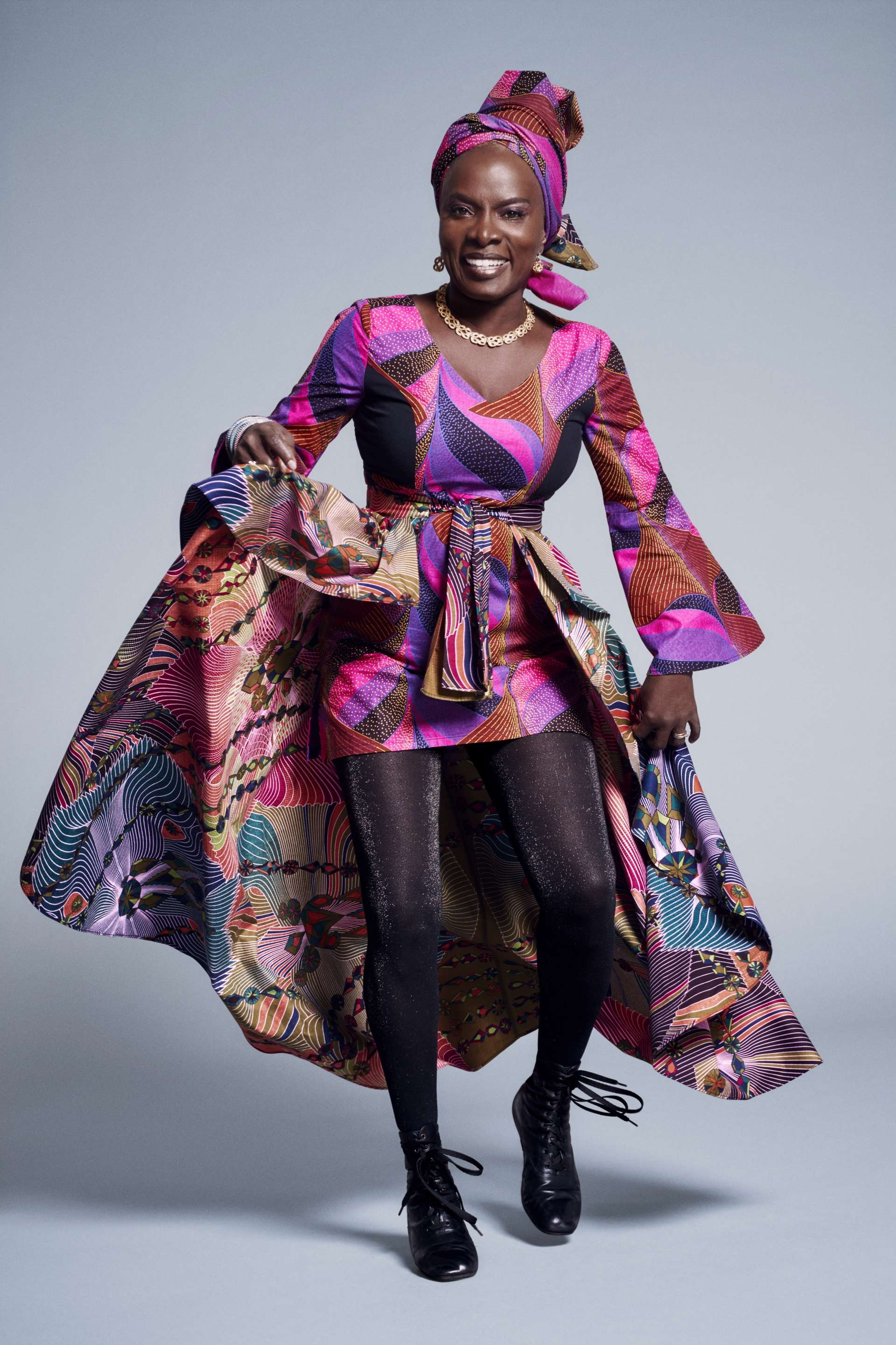 Photo de studio d'Angélique Kidjo. La chanteuse porte une tenue colorée et traditionnelle africaine. 