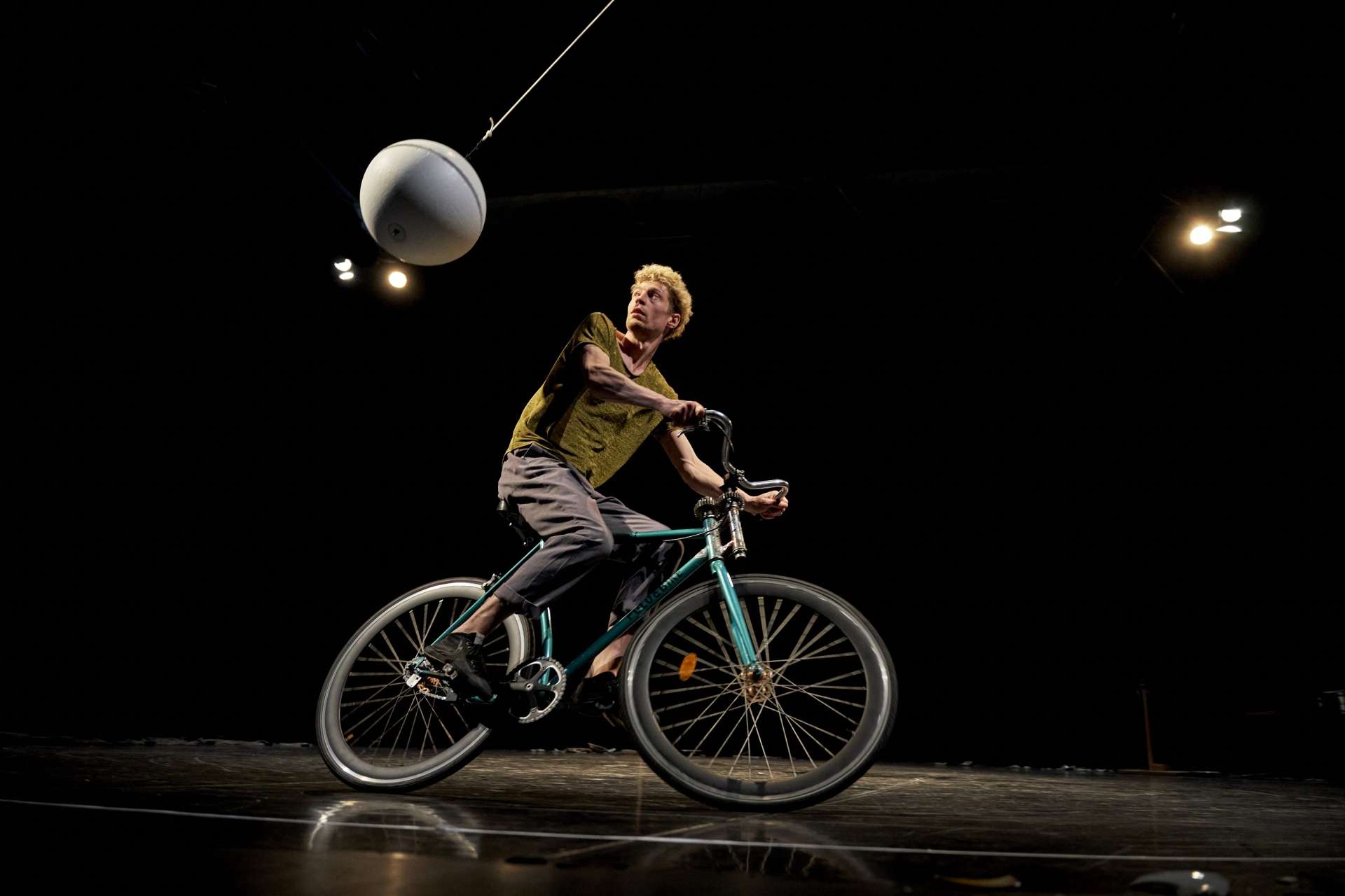 Un homme fait du vélo alors qu'une grosse boule blanche tourne autour de lui. 