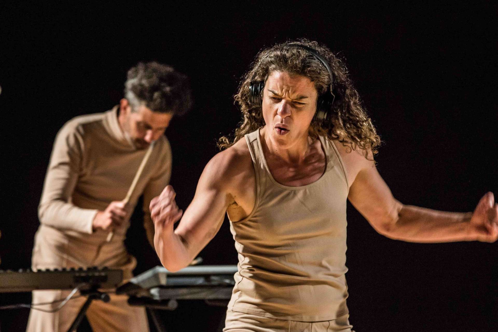 Une femme ou un homme danse au premier plan, il s'agit de Juglair. Au second plan, le musicien Lucas Barbier enregistre des sons sur un pad numérique. 