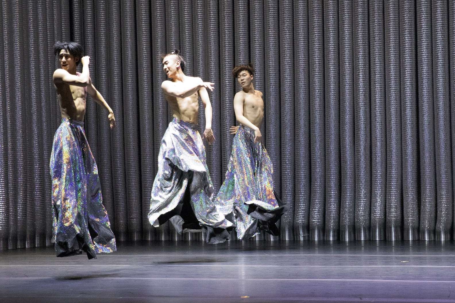 Trois danseurs asiatiques semblent suspendus dans les airs. 