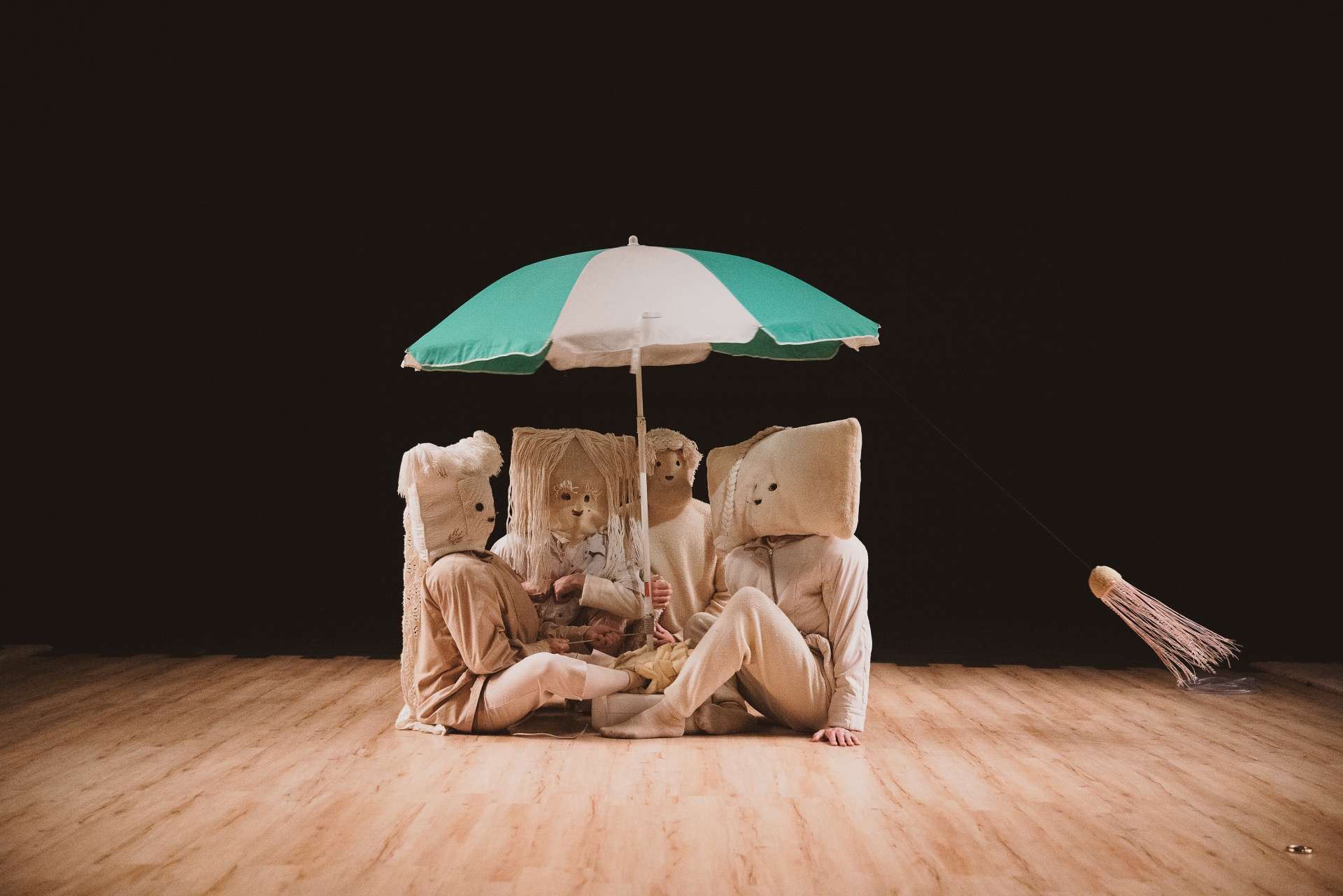 Photo du spectacle La Maison de mon esprit où les 4 personnages sont assis sous un parasol vert et blanc