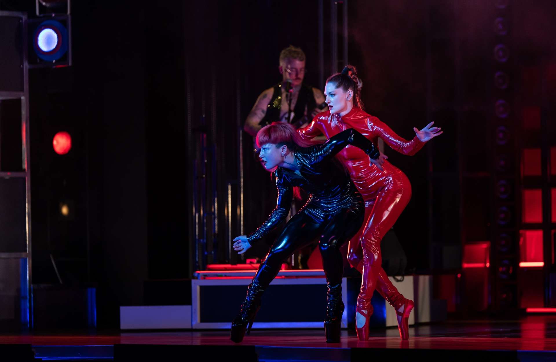 Duo de deux danseuses en combinaisons en latex. L'une en noir avec des chaussures de Drag Queen et la seconde une combinaison rouge et des pointes classiques. 