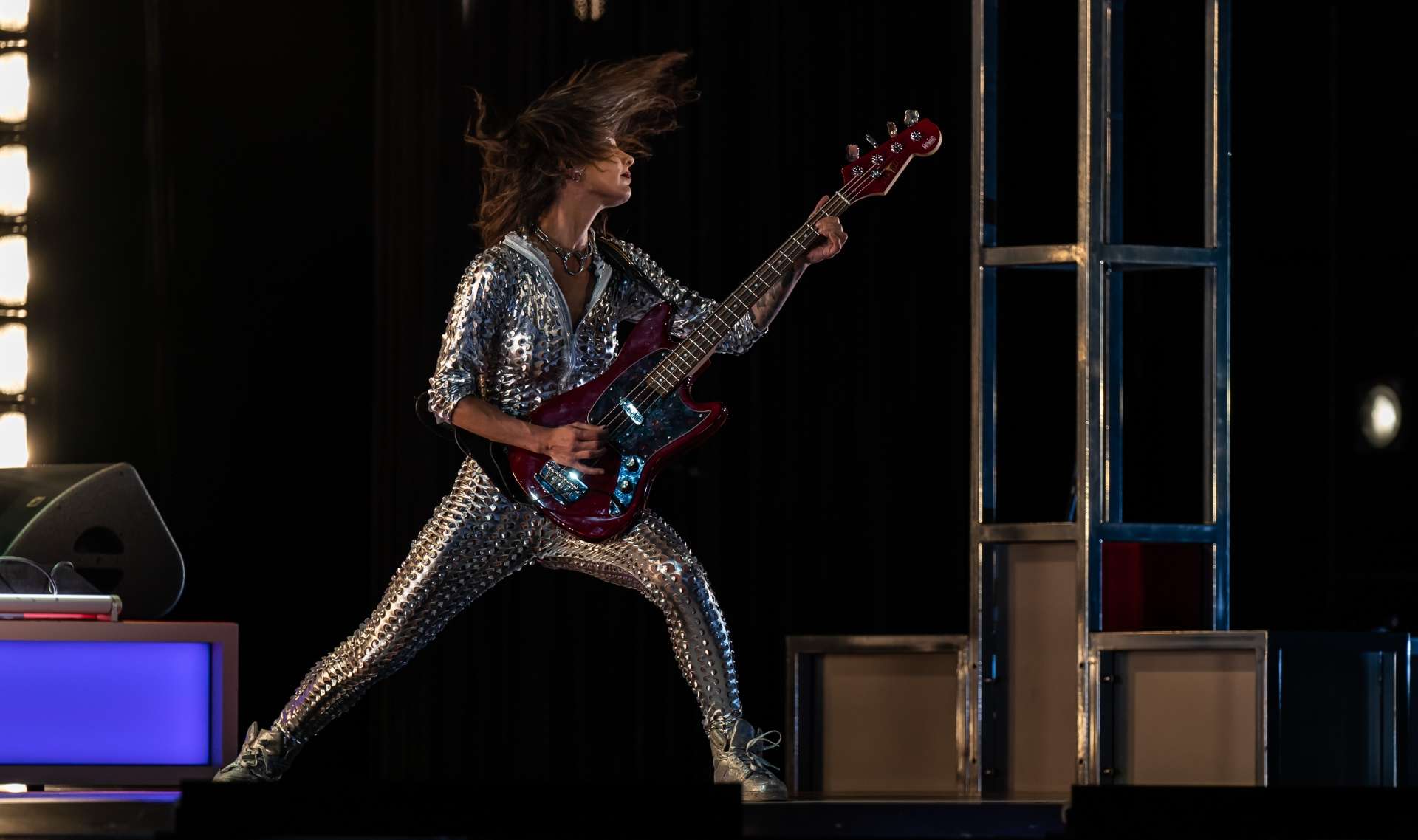 Dans un costume moulant argenté, la guitariste a une posture de rockstar. 