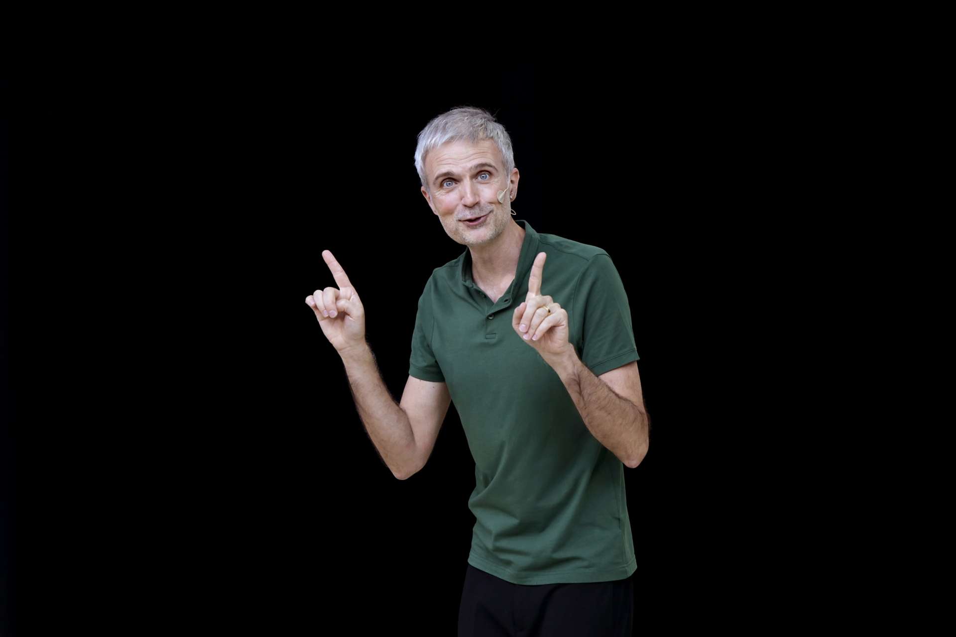 Un homme au centre avec un T-shirt vert parle avec les mains