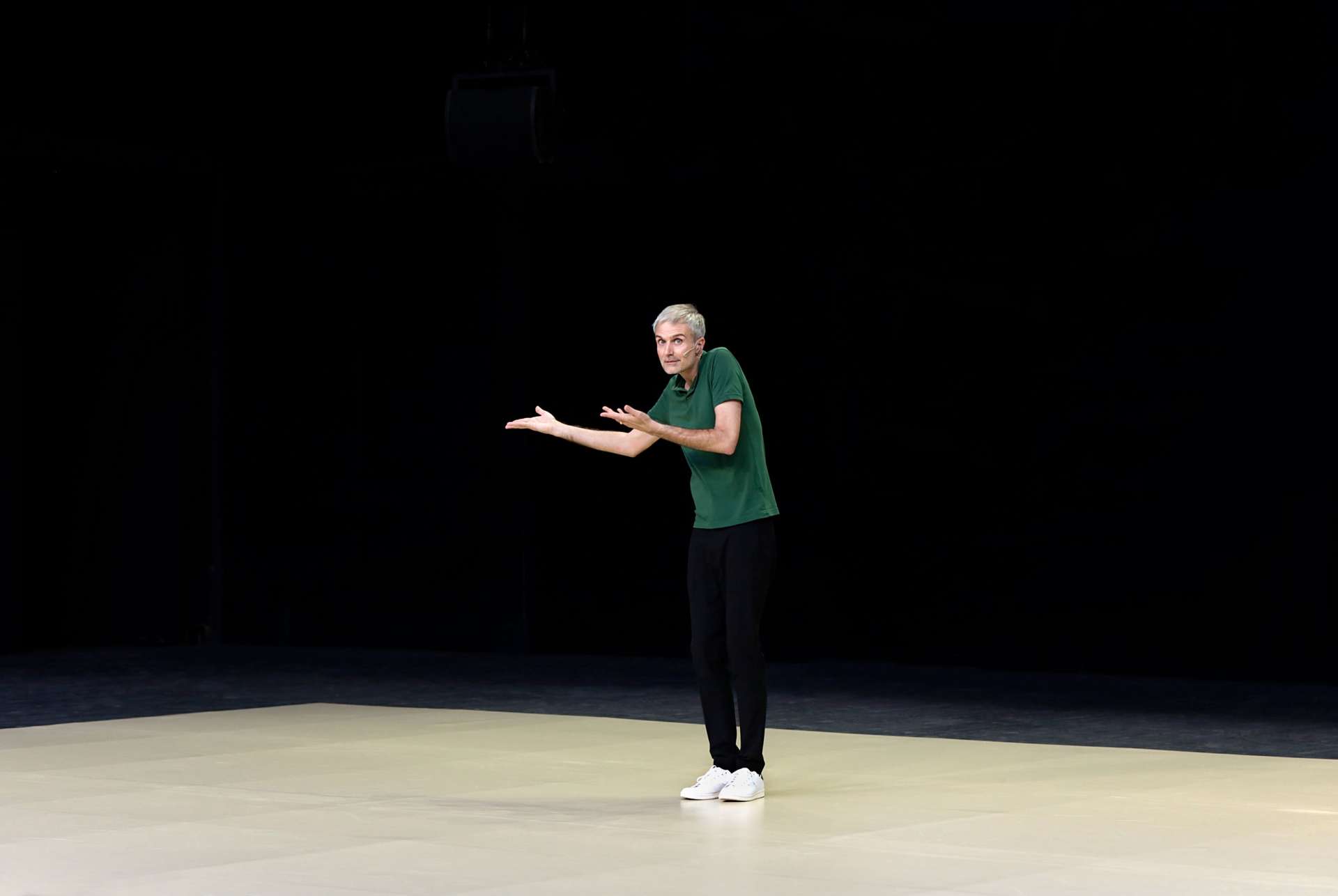 Un homme au centre avec un T-shirt vert parle avec les mains