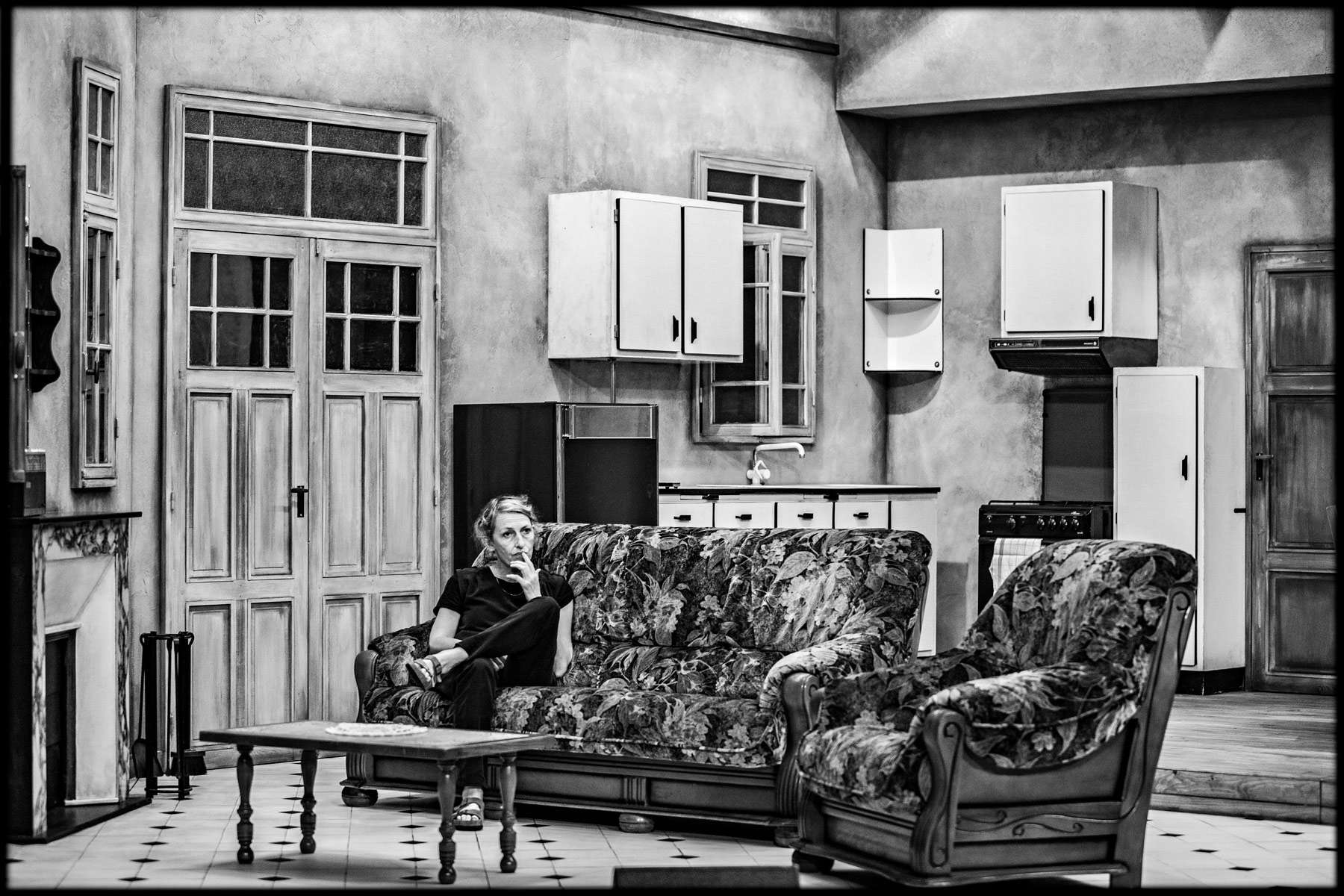 Dans un décor en noir et blanc une femme pensive dans un canapé