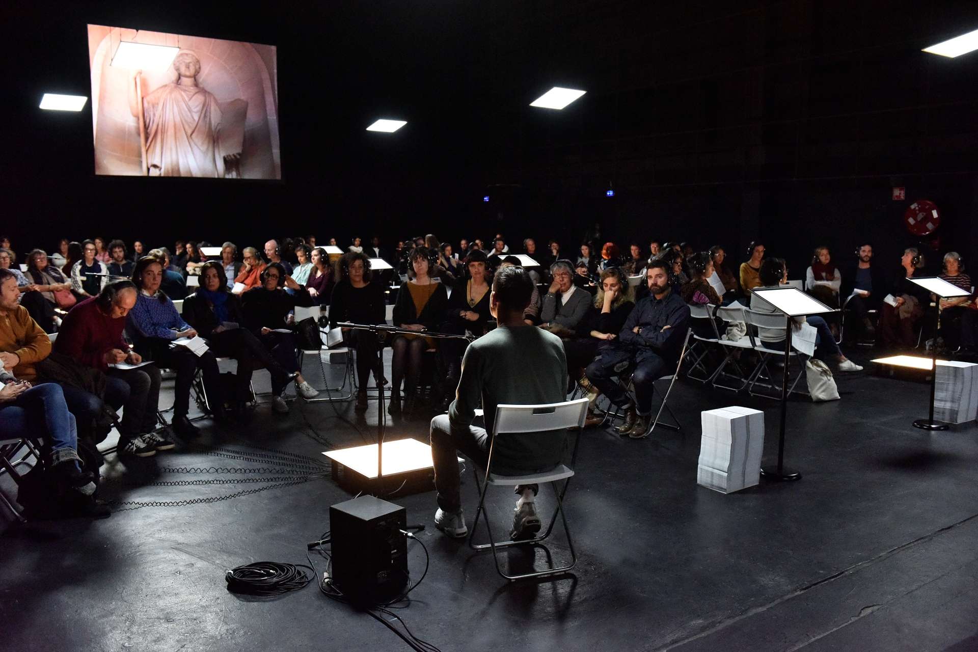 Salle avec des chaises et des personnes qui écoutent avec des casque sur les oreilles