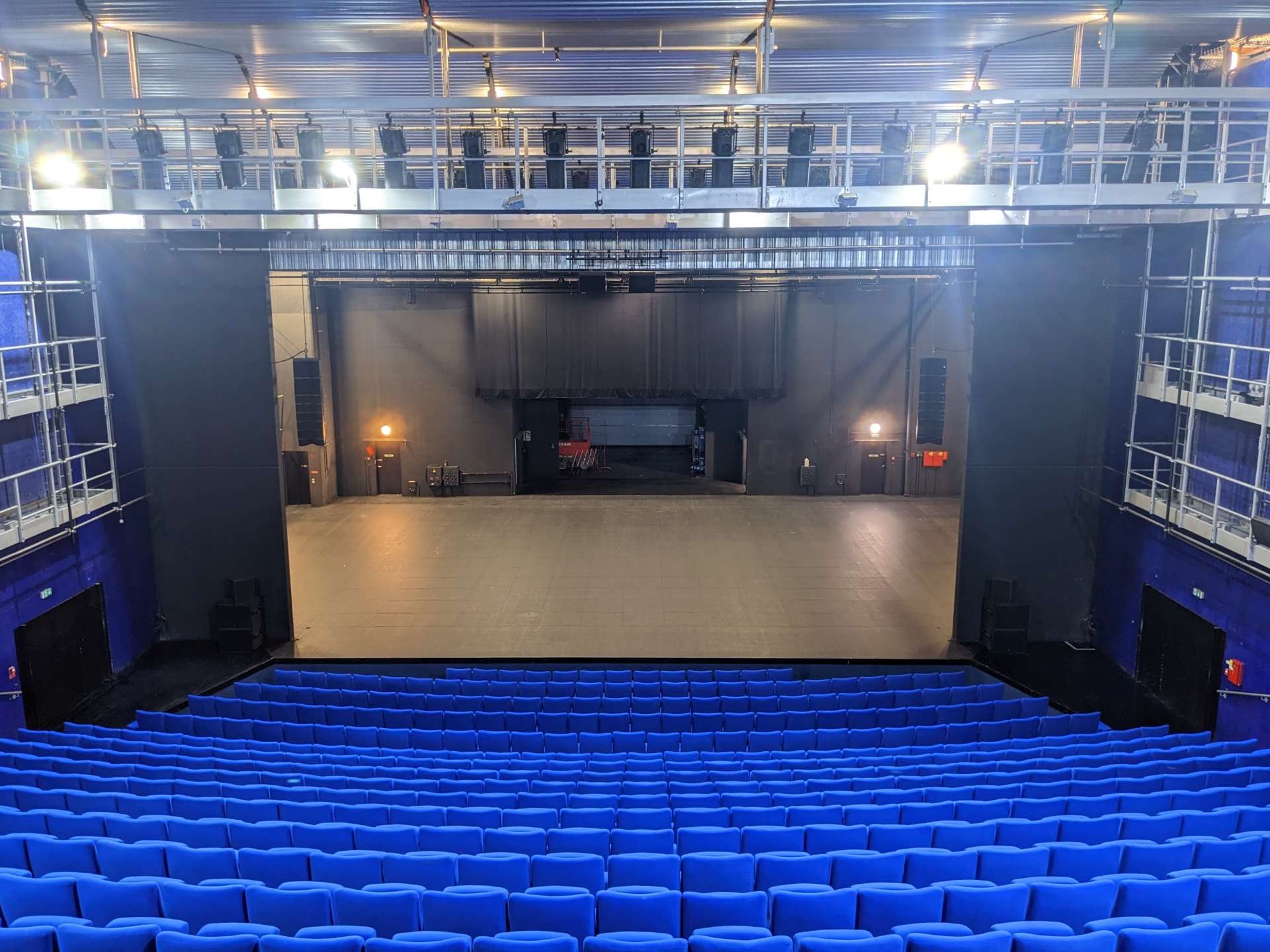 Vue de la salle Barrault côté salle avec au premier plan les fauteuils bleus et au second le plateau. 