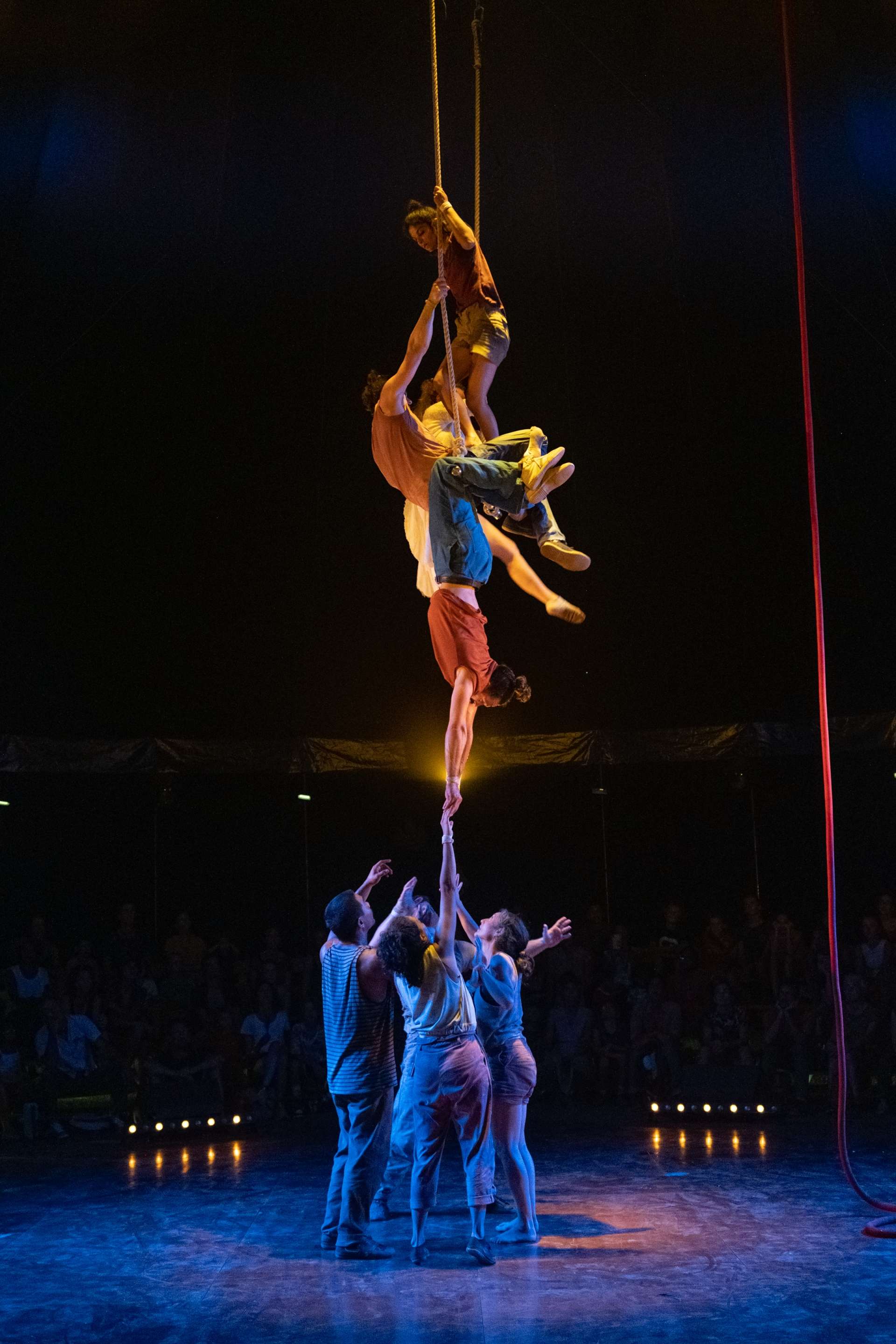 Suspendus en l'air, des acrobates tentent d'attraper celles et ceux restés au sol ou peut-être l'inverse. 