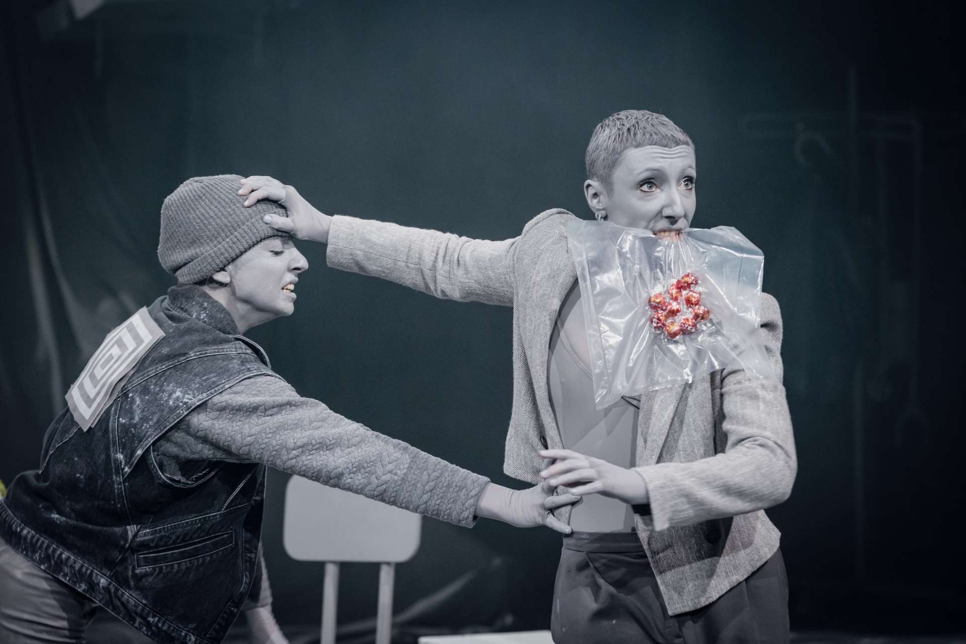 Photo dans les monochromes de gris. Deux femmes semblent se disputer. L'une d'entre elle tient un sachet dans la bouche, l'autre cherche à le récupérer.