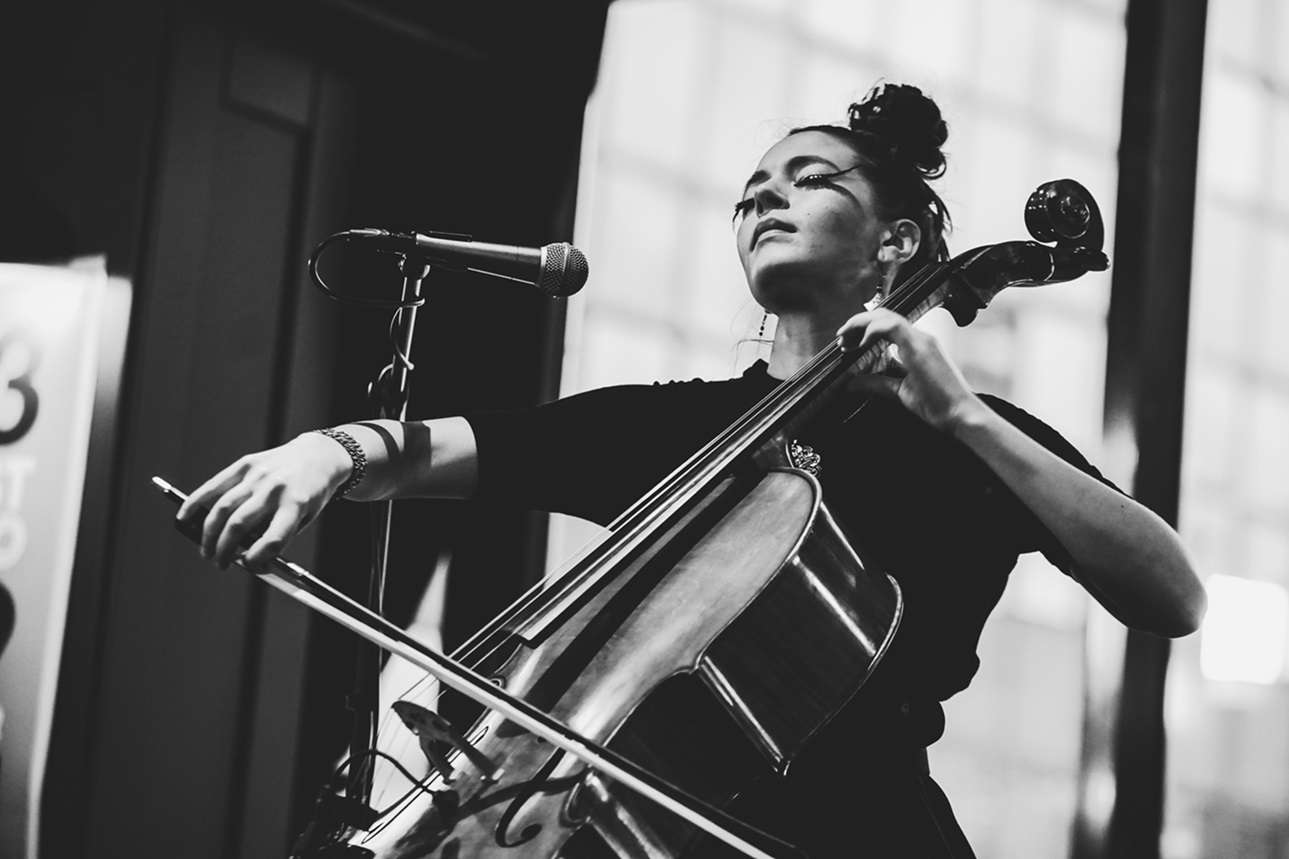 Photo en noir et blanc de Lana Kostic qui joue du violoncelle sur scène. 