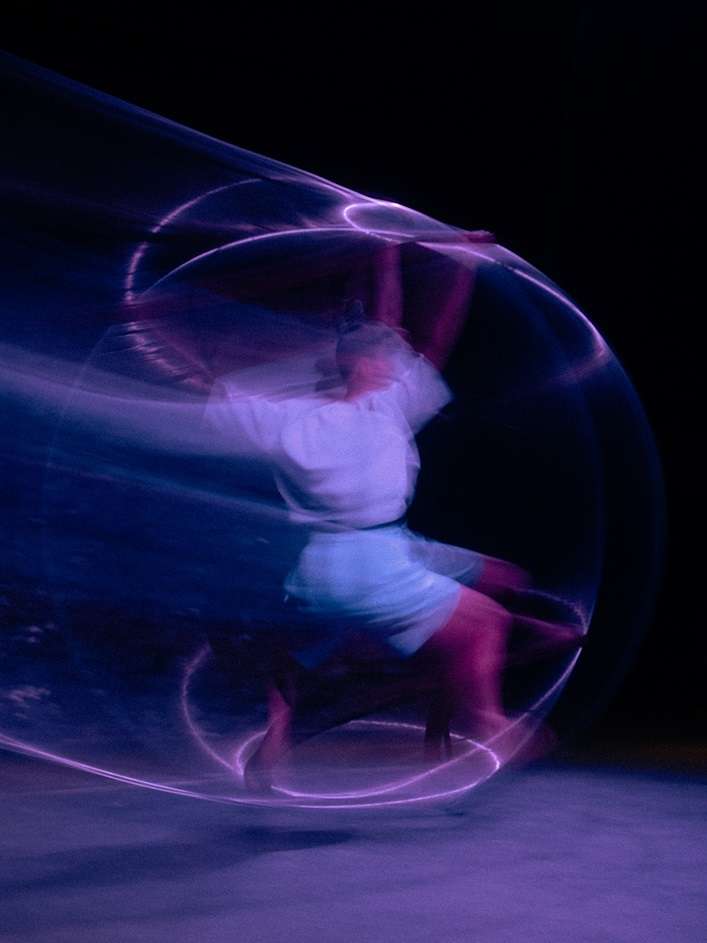 Photo floutée d'une femme sur roue Cyr, en mouvement. 